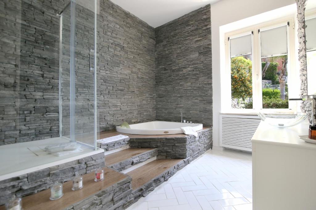 a bathroom with a bath tub and a stone wall at Hotel Marincanto in Positano