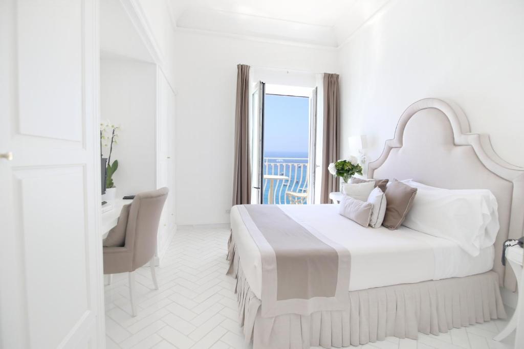 a white bedroom with a large bed and a desk at Hotel Marincanto in Positano