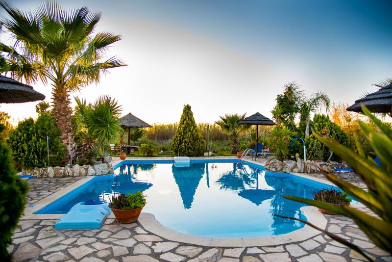 a large swimming pool with blue chairs and palm trees at Villa Swan in Lefkada