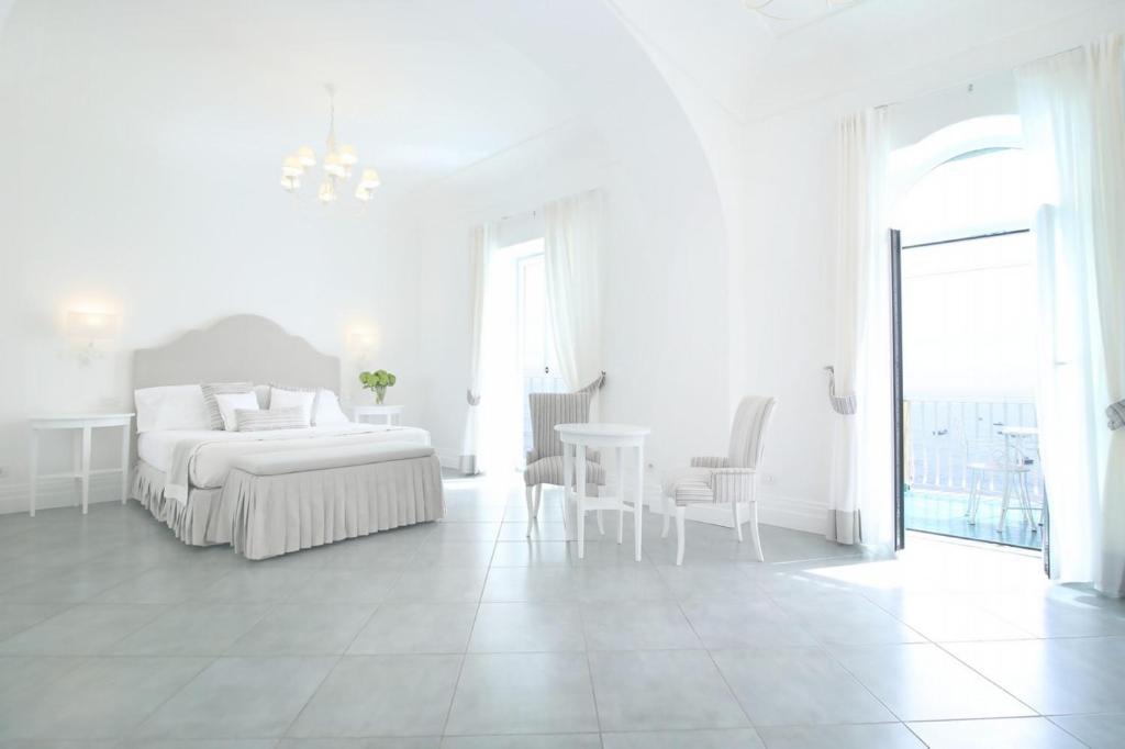 a white bedroom with a bed and a table and chairs at Hotel Marincanto in Positano