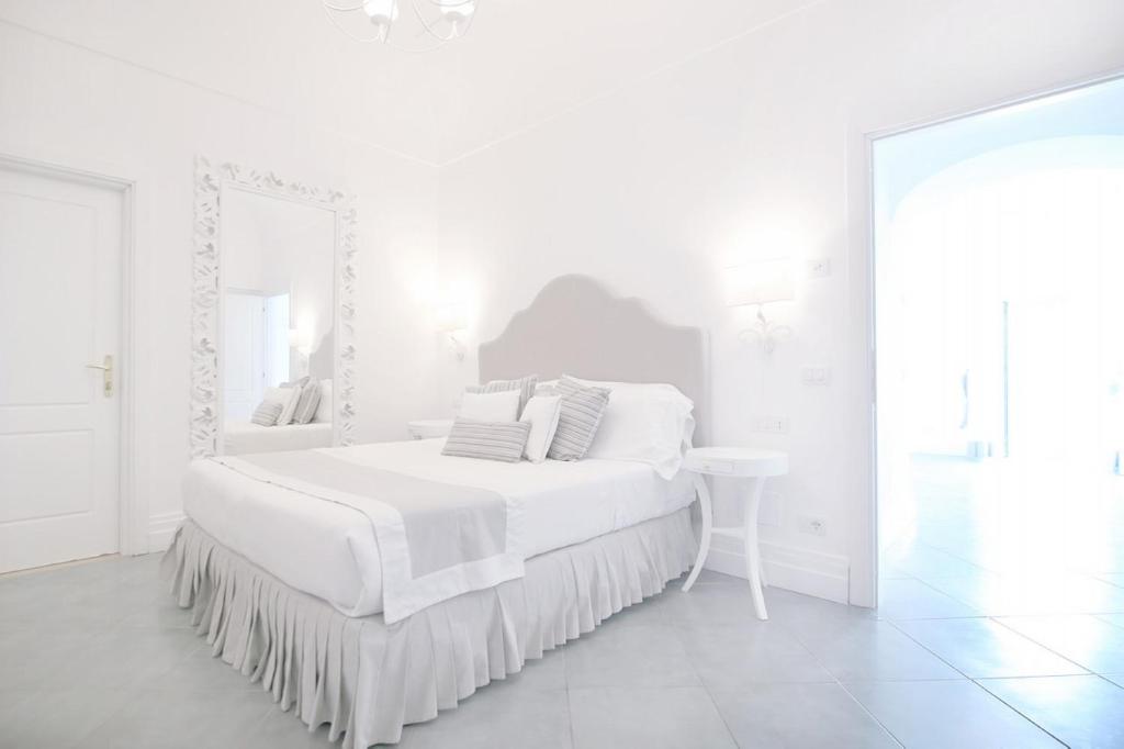 a white bedroom with a large white bed and a mirror at Hotel Marincanto in Positano