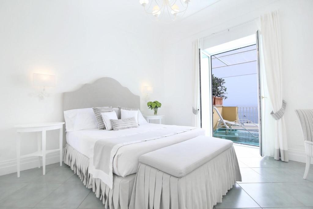 a white bedroom with a bed and a large window at Hotel Marincanto in Positano