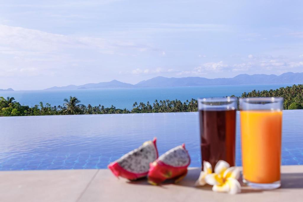 a glass of orange juice and two pieces of fruit at villa Siam View Samui in Ban Bang Po