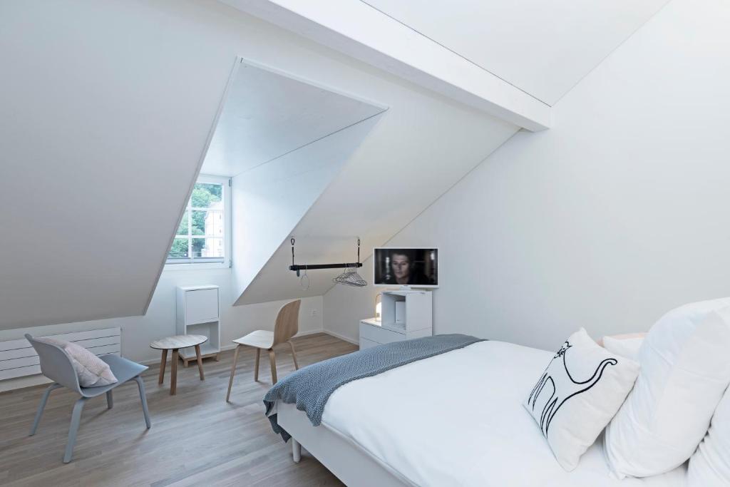 a white bedroom with a bed and chairs at Dom Studios in St. Gallen