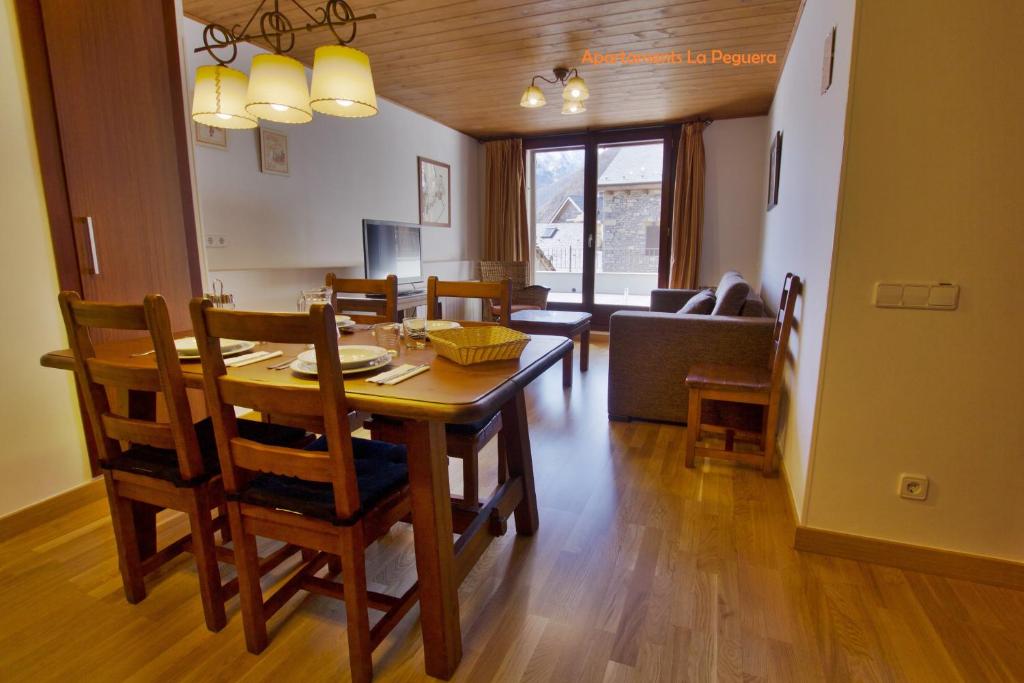 a dining room and living room with a table and chairs at Apartaments La Peguera II in Barruera