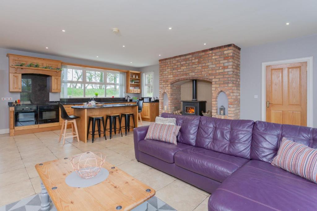 uma sala de estar com um sofá roxo e uma cozinha em Glenside Lodge em Ballymena