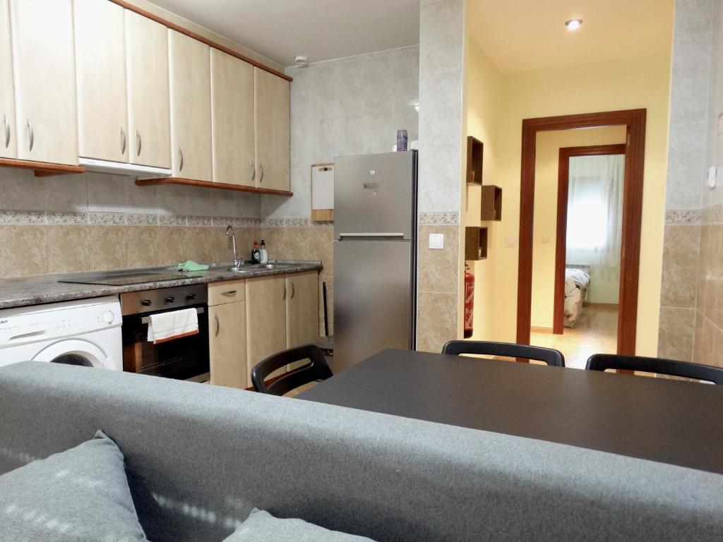 a kitchen with a table and a stainless steel refrigerator at Apartamento del Rosario in Corella