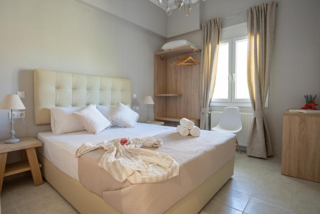 a bedroom with a large bed with white sheets and a window at ILIOS apartment in Nydri