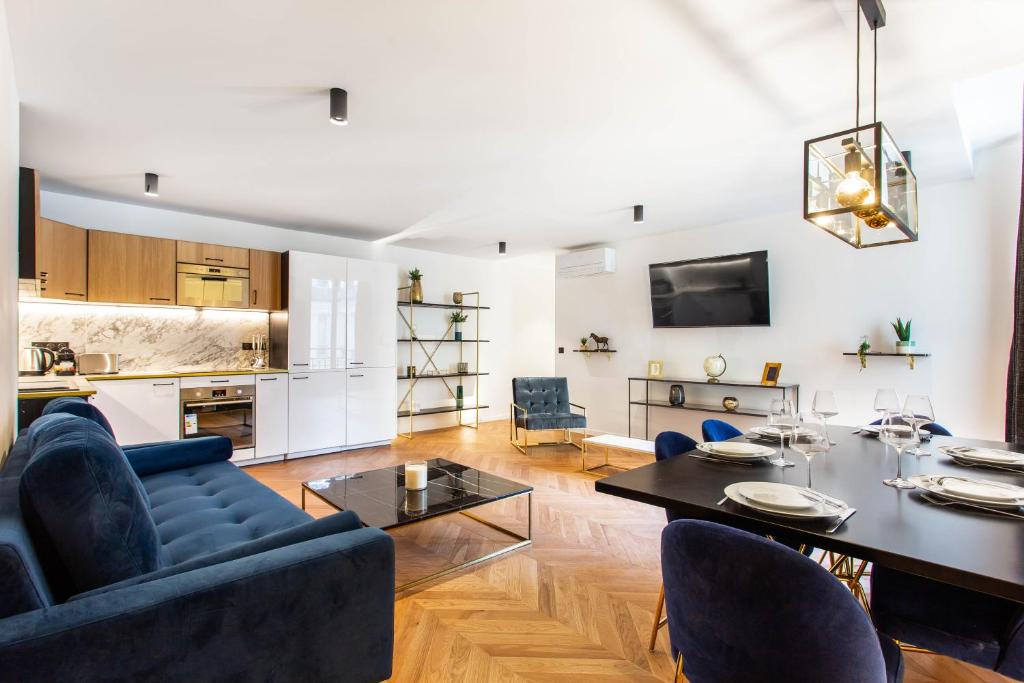 ein Wohnzimmer mit einem Tisch und blauen Stühlen in der Unterkunft CMG Champs Elysées - Boetie 6 in Paris