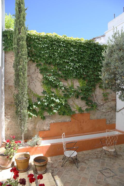 a patio with two chairs and a wall with plants at RONDAPLACE in Ronda