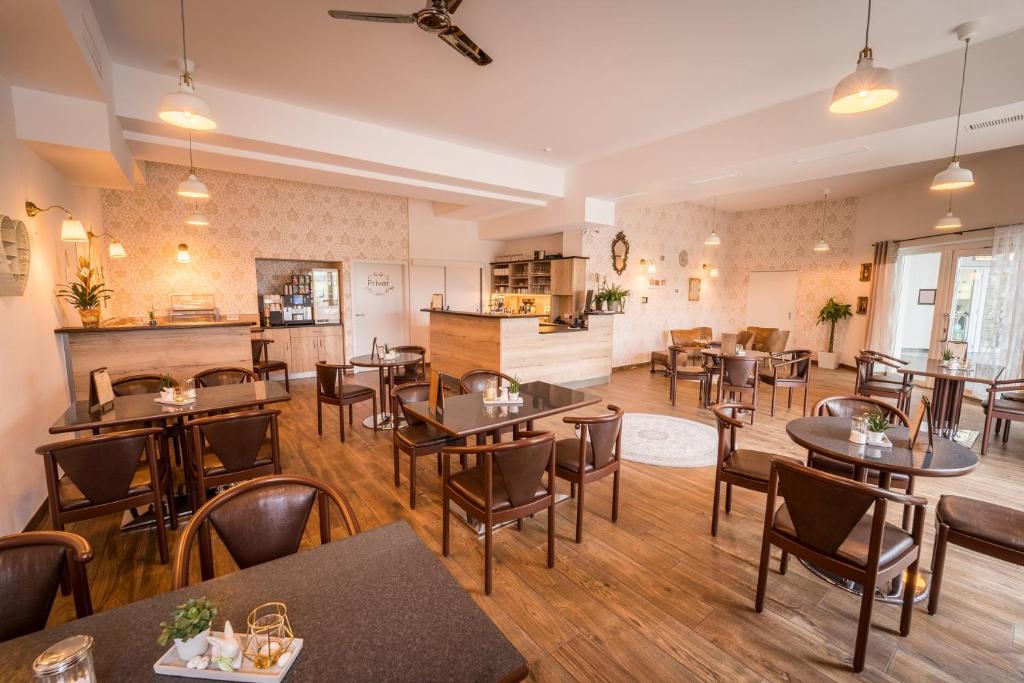 ein Restaurant mit Tischen und Stühlen in einem Zimmer in der Unterkunft Hotel Café Nahetal - Hotel garni in Gensingen