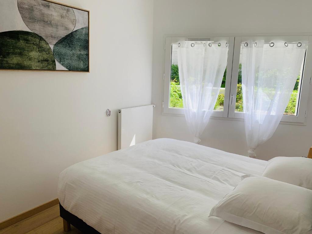 a white bedroom with a bed and two windows at ALPS COCOON in Annecy