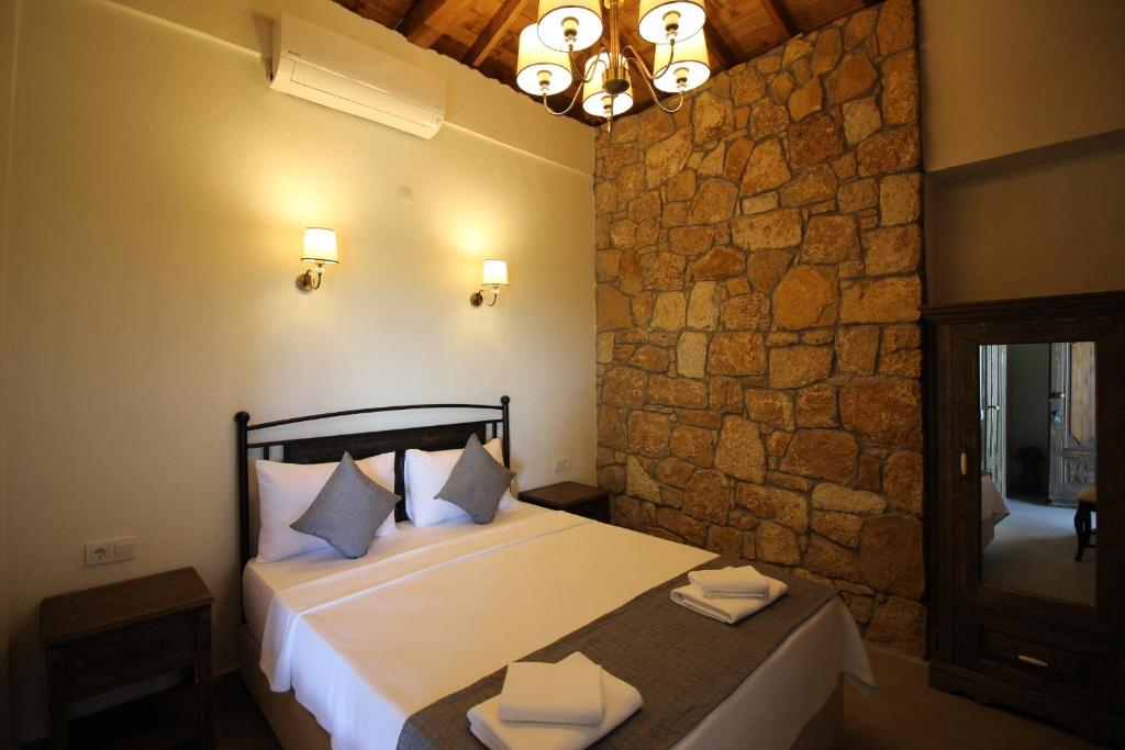 a bedroom with a bed and a stone wall at Bozcaada Defne Bağ Evi in Bozcaada