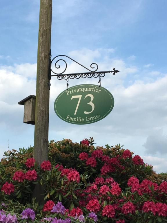 a sign hanging from a pole next to flowers at Privatquartier 73 in Wietzen