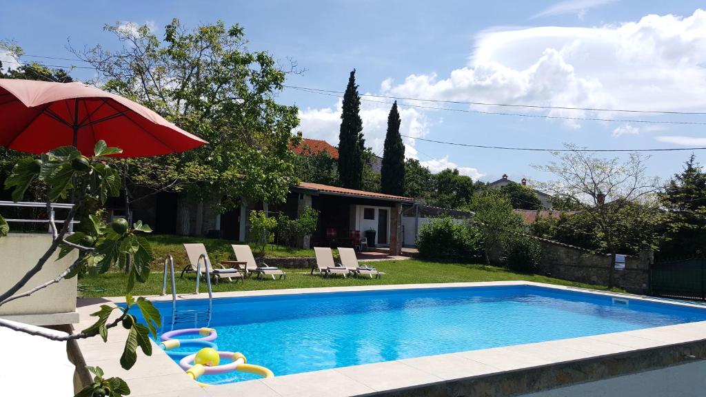 a swimming pool with an umbrella and chairs and a house at Casa Bellavista in Rijeka
