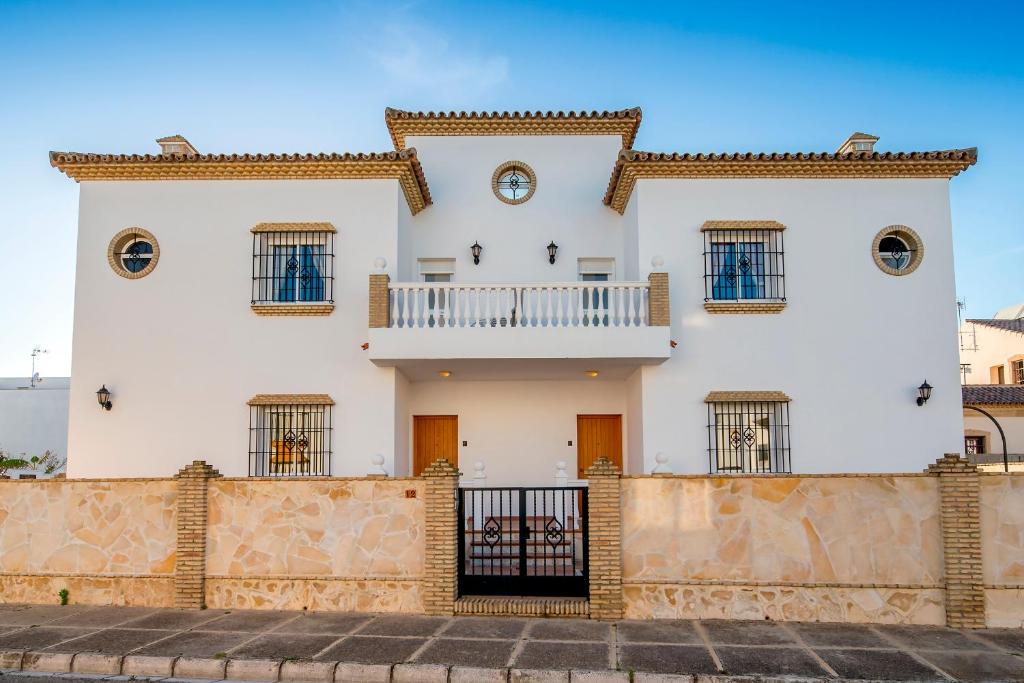 een wit huis met een hek ervoor bij Chalet adosado Atalaya P in Conil de la Frontera