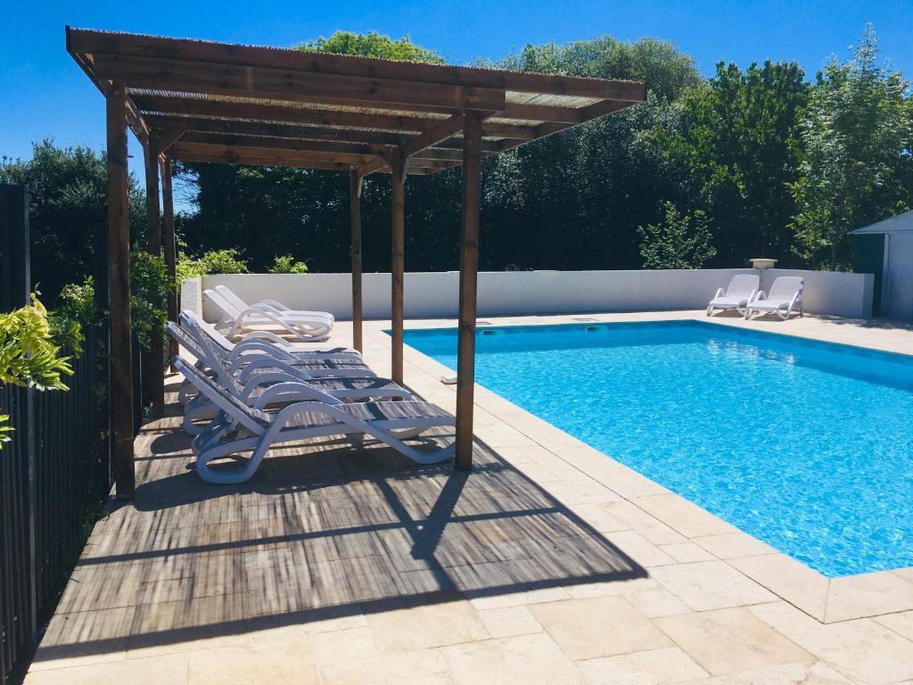 a group of chairs under a pavilion next to a swimming pool at Gîtes Les Neuf Cerisiers in Mascaras