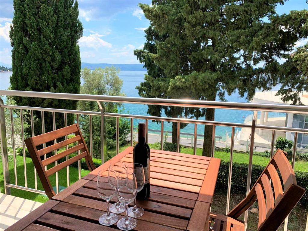 a wooden table with a bottle of wine and two glasses at Apartmani Heta Alagic I in Selce