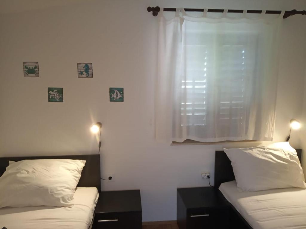 - une chambre avec 2 lits et une fenêtre avec des rideaux dans l'établissement Apartments Maduna, à Punat
