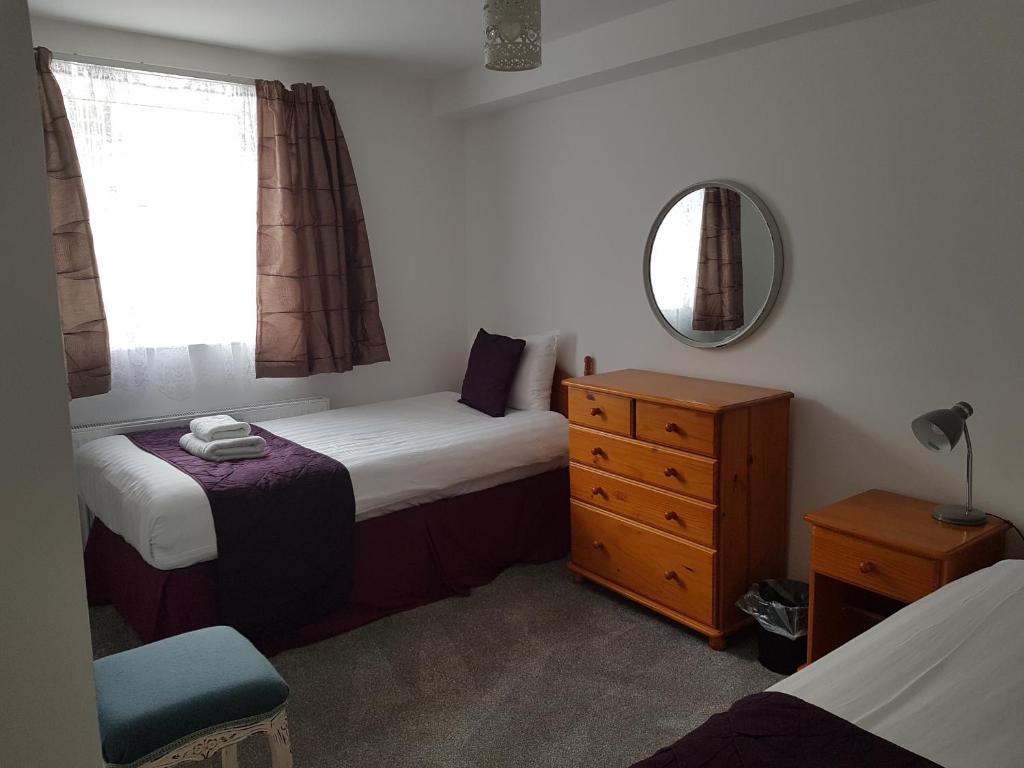 a bedroom with two beds and a dresser and a mirror at Runnacleave Court, apartment 2 in Ilfracombe