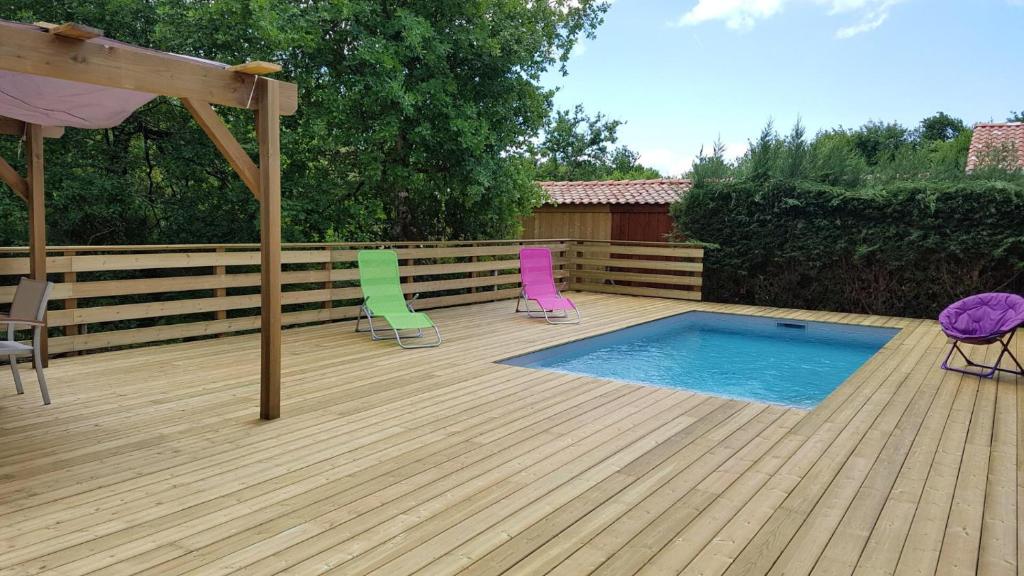 twee stoelen en een zwembad op een houten terras bij comme chez vous in Taussat-les-Bains