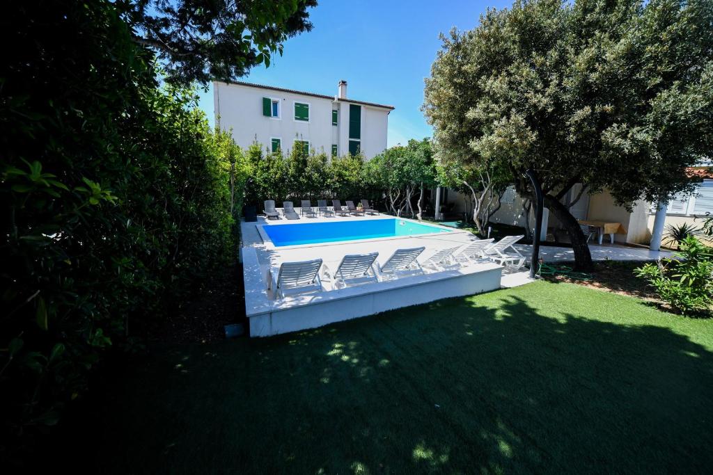 a backyard with a swimming pool and chairs at Apartments Dvori Novalja in Novalja