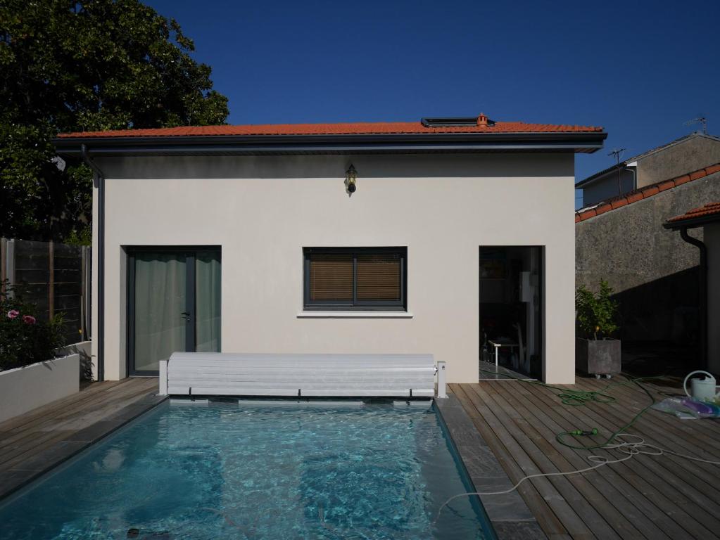 une piscine avec un banc devant une maison dans l'établissement Duplex avec piscine, à Villenave-dʼOrnon