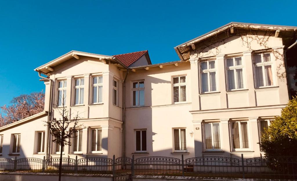 a large white house with a black fence at Ferienwohnungen Hennig in Heringsdorf