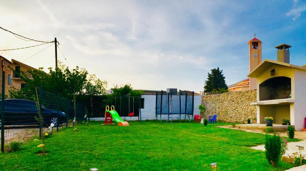 une cour avec une aire de jeux avec un toboggan dans la pelouse dans l'établissement Apartment Baćo, à Podstrana