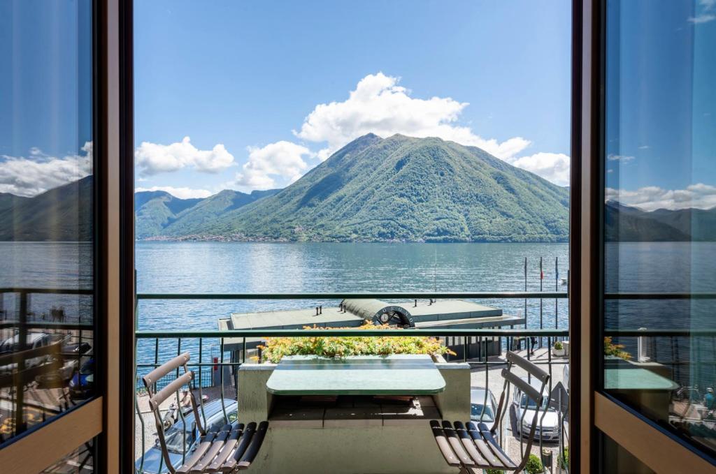 uma varanda com uma mesa e cadeiras e vista para uma montanha em Hotel Argegno em Argegno