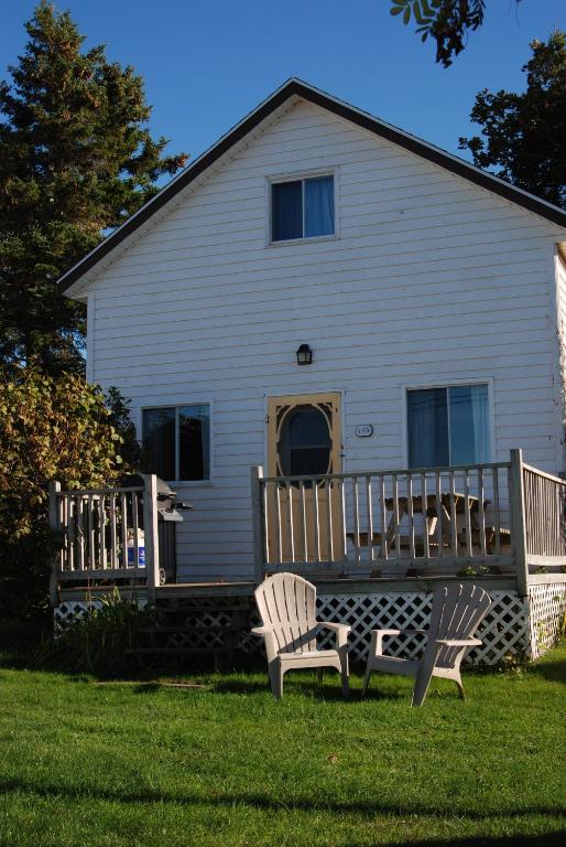 two chairs sitting in the grass in front of a house at Shining Waters - Ingleside Cottages in Cavendish
