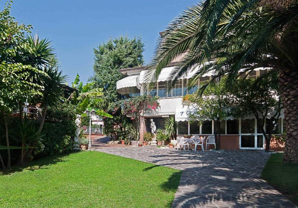a house with a palm tree in front of a yard at La Chandelle in Massarosa