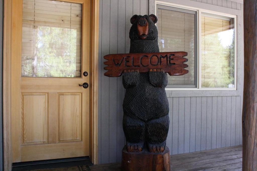 une statue d'ours tenant un panneau de bienvenue devant une porte dans l'établissement Deer - 19, à Sunriver