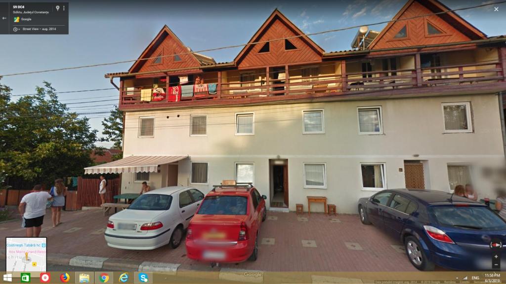 a large building with cars parked in a parking lot at Pension AMIRA in Costinesti