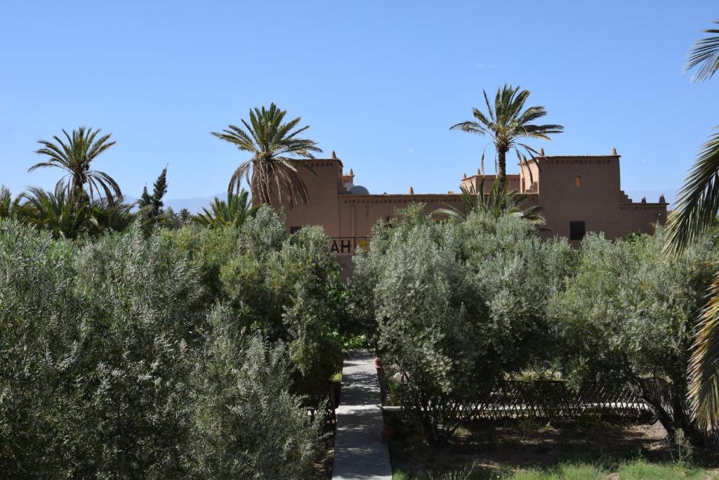 einen Garten mit Bäumen und ein Gebäude im Hintergrund in der Unterkunft kasbah 123 soleil in Skoura