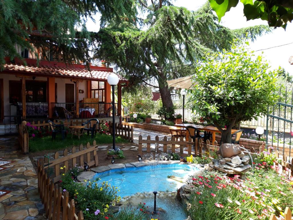 a garden with a small pool in front of a house at Handmade peaceful cozy house near the beach in Nea Kalikratia