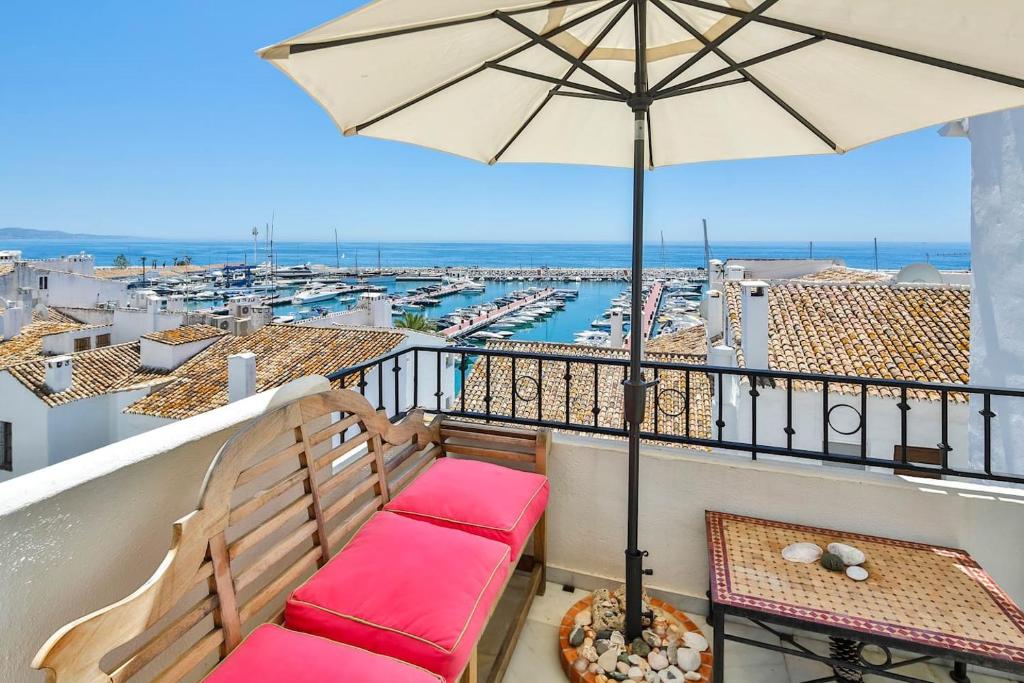 balcón con banco y sombrilla en Puerto Banus Harbour View Apartment en Marbella