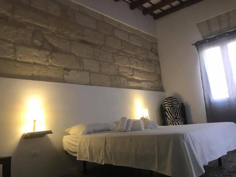 a bedroom with a large bed with two lamps at Le Case Del Grillo in Trapani