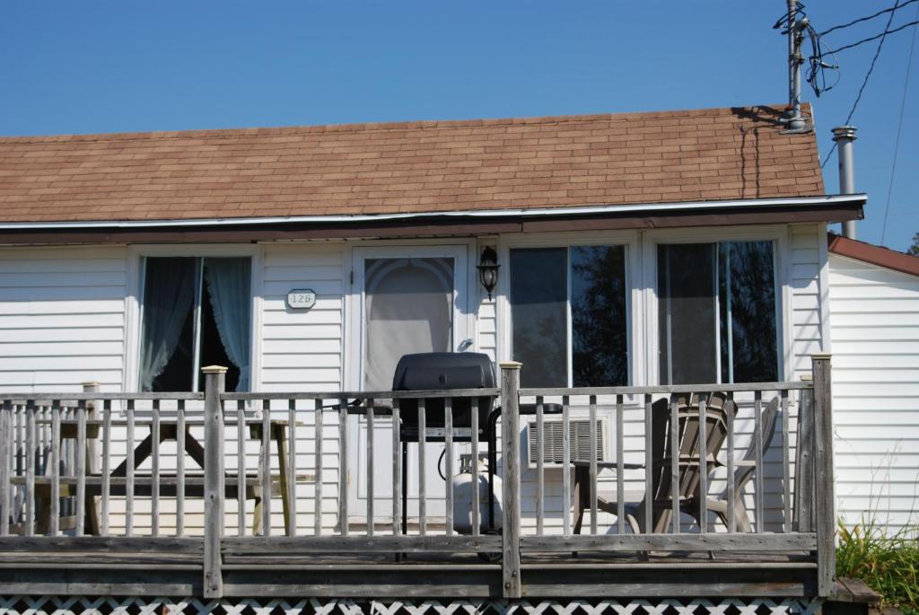 a white house with a porch with chairs on it at Shining Waters - Ingleside Cottages in Cavendish
