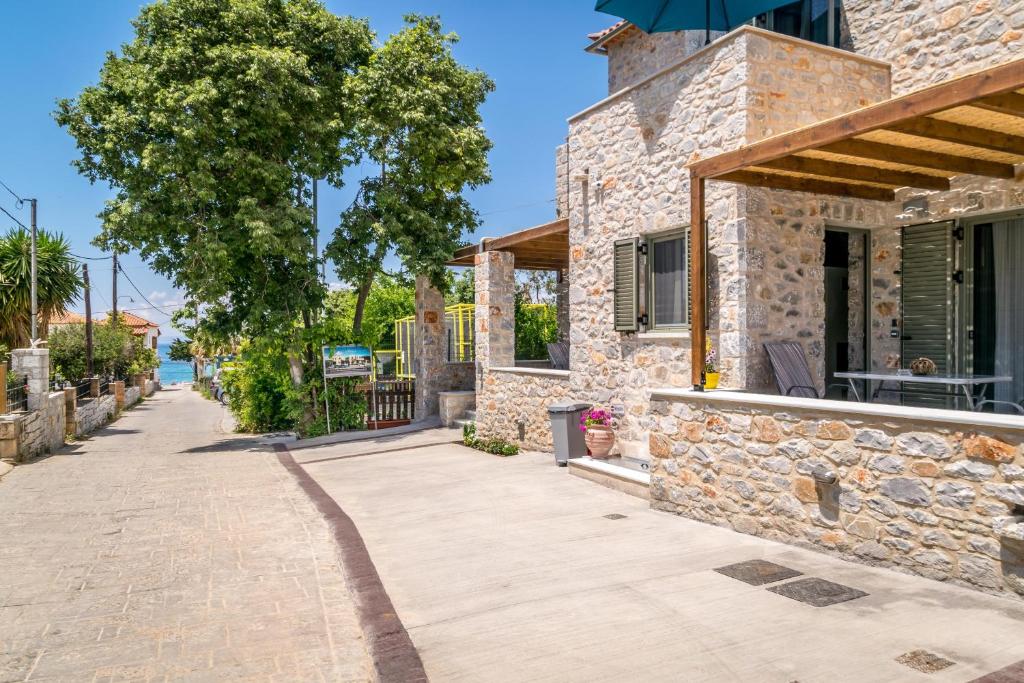 a stone building with a tree and a sidewalk at Petras Gi - Stone Houses in Stoupa