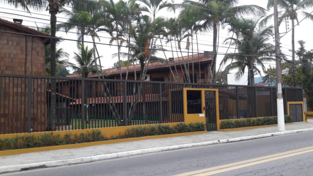 ein Zaun an der Seite einer Straße mit einem Gebäude in der Unterkunft Condomínio frente ao mar in Boicucanga
