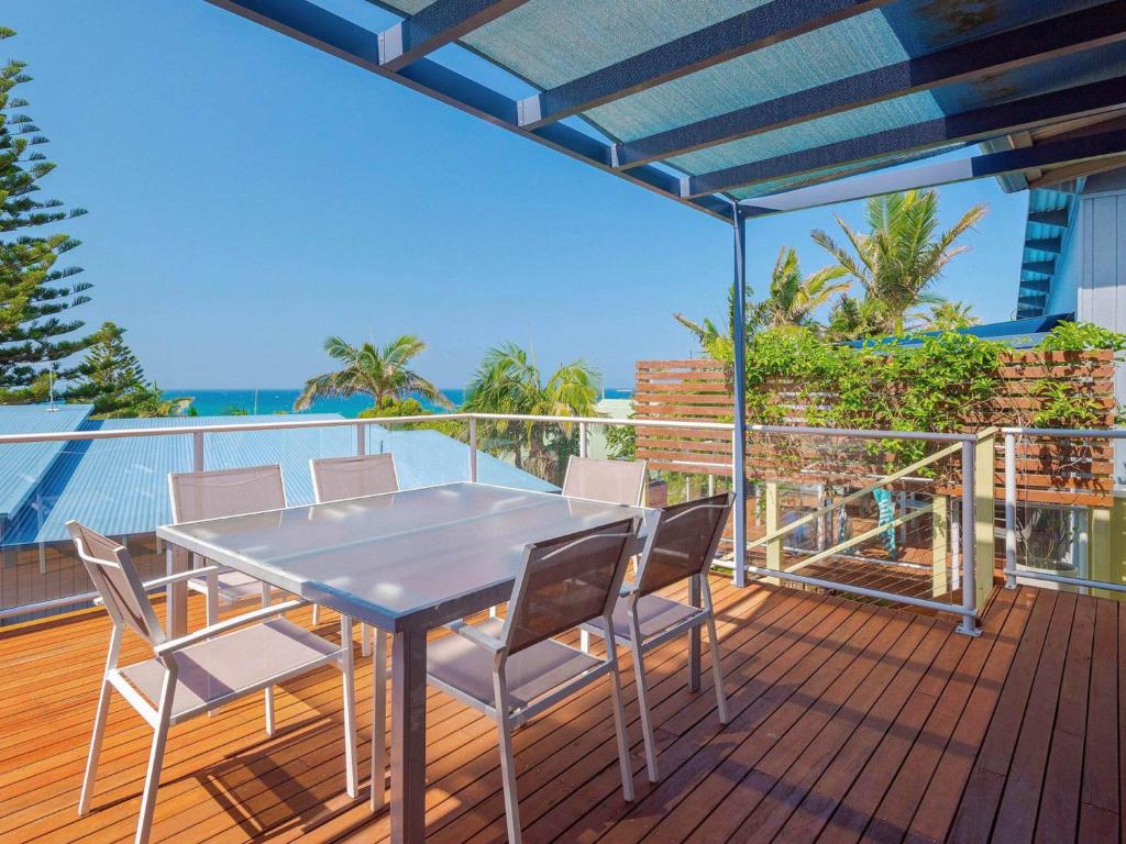 a table and chairs on a deck with a view of the ocean at Angourie Blue 4 in Yamba
