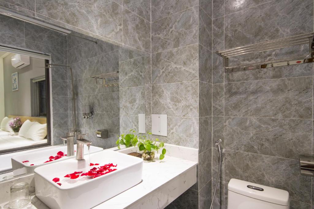 A grey-tiled bathroom with a vessel sink, toilet and open shower area.