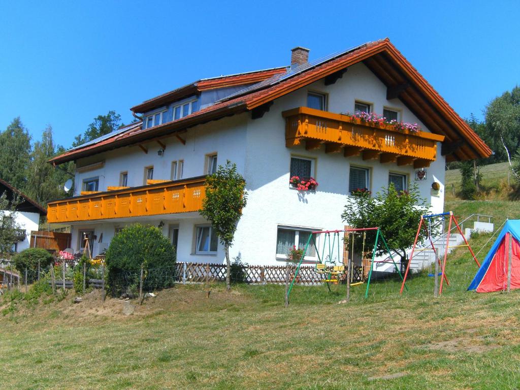 una gran casa blanca con un parque infantil delante de ella en Pension Reindlhöh, en Lohberg