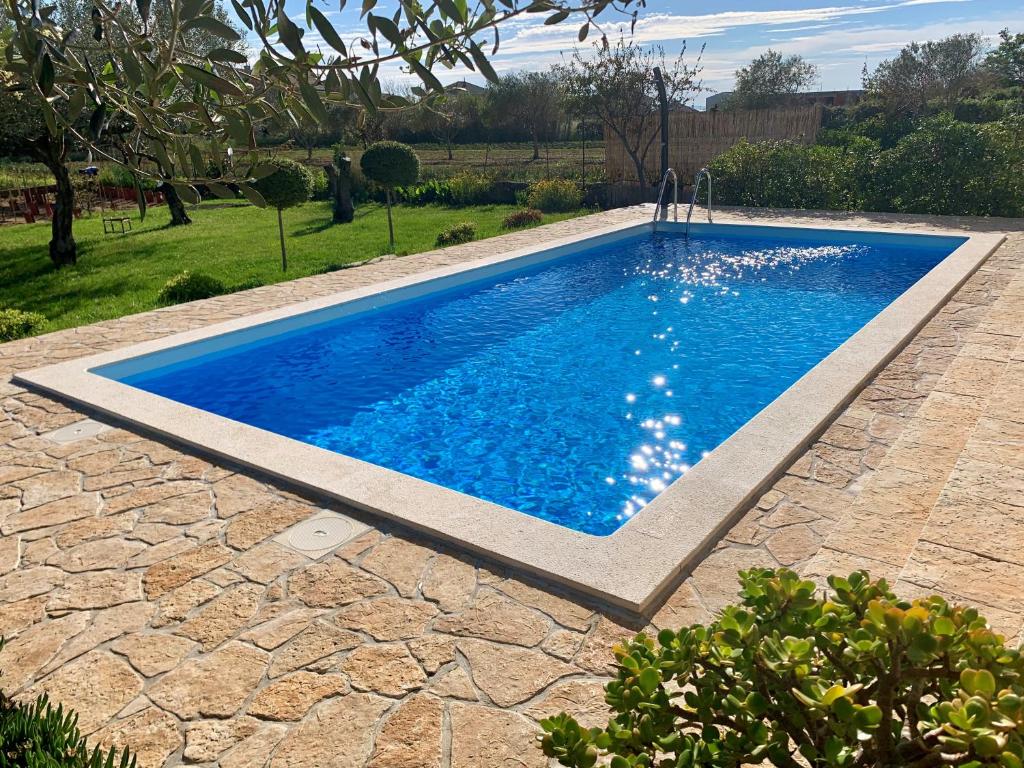 a swimming pool with blue water in a yard at Bed&Breakfast Nada in Privlaka