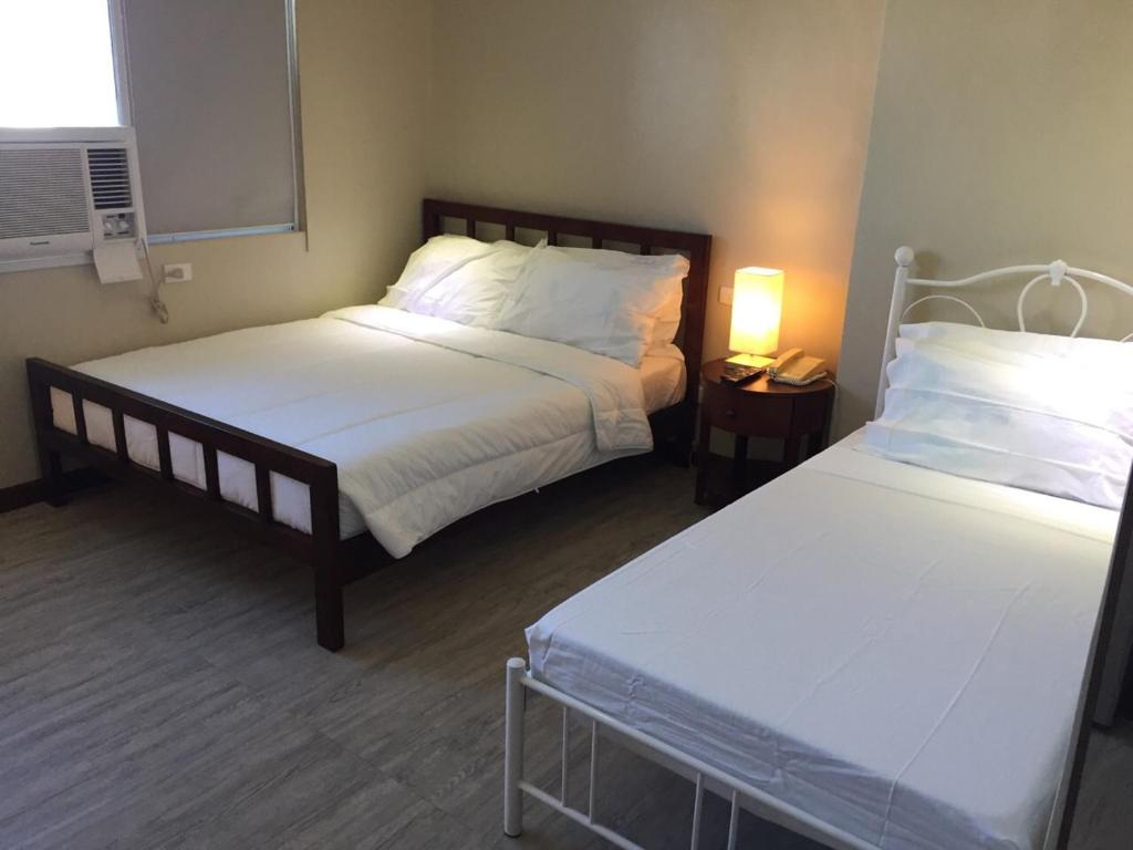 a bedroom with two beds and a night stand with a lamp at GOLDEN PEAK CONDO in Cebu City
