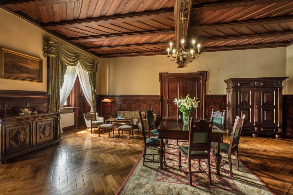 Elegant dining room with wooden furniture, chandelier, and large windows with draped curtains.