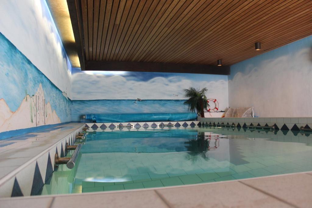 a swimming pool in a building with a large swimming pool at Ferienhaus Abbi mit Schwimmbad und Fitness für 8 Personen, Strand, Norddeich in Hage