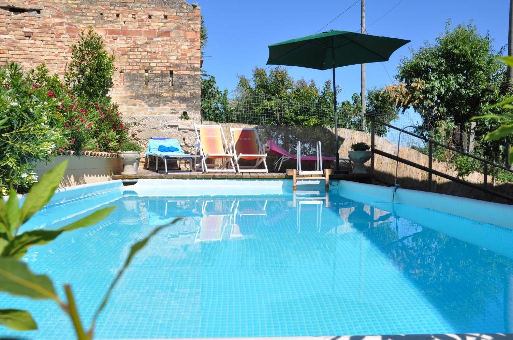 a swimming pool with two chairs and an umbrella at Bed and Breakfast Latteletto in Tortoreto Lido