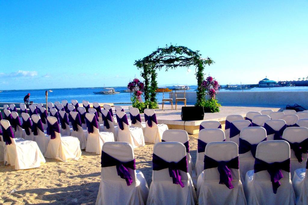 a wedding ceremony on the beach with white chairs at BE Resort Mactan in Mactan